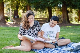 two students studying outdoors on the lawn